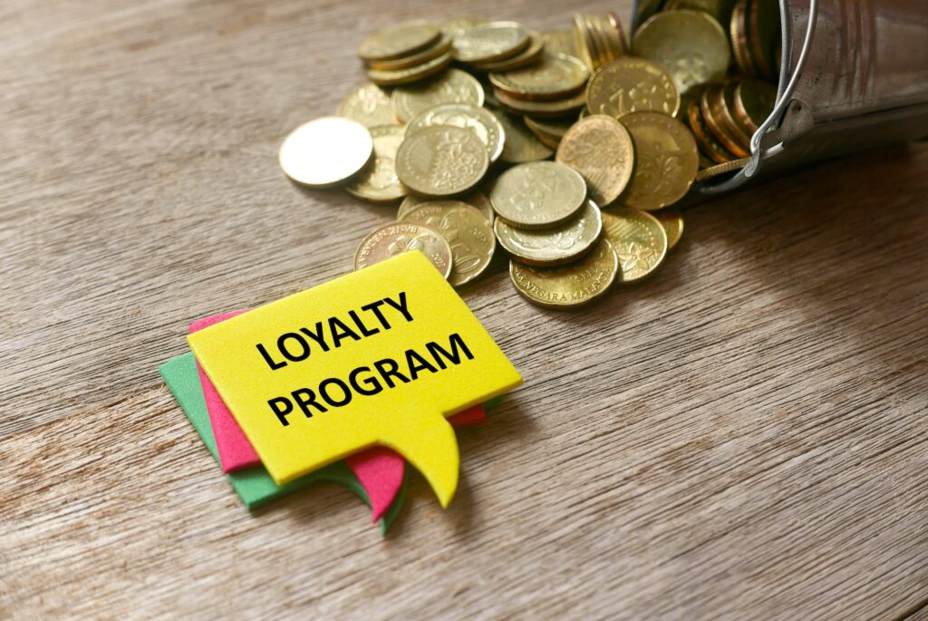 Gold coins and a stack of speech bubbles written with Loyalty Program on wooden background.